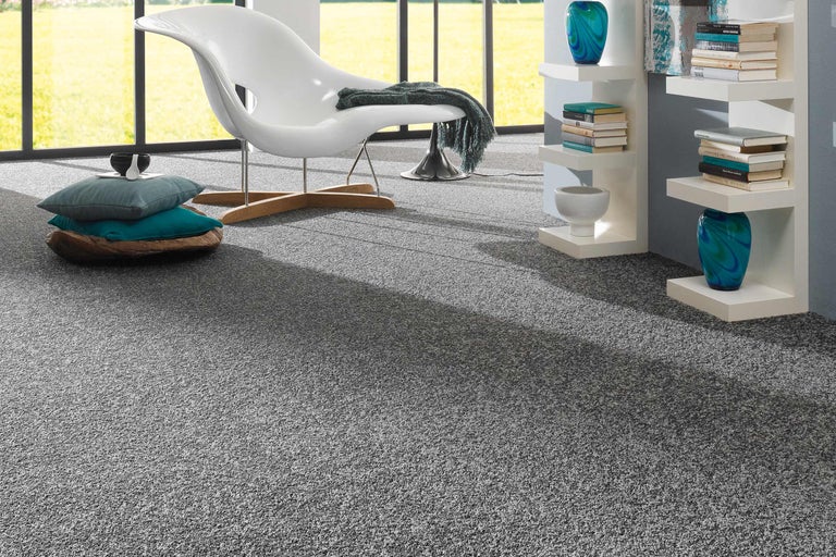 Innenraumszene mit grauem Teppichboden, Sessel und dekorativen Elementen