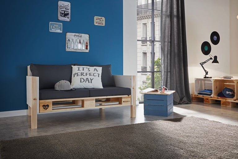 Wohnzimmer mit Palettensofa, Couchtisch und Dekorationen an der Wand