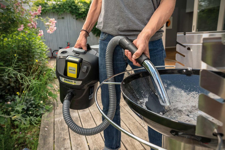 Eine Person reinigt einen Grill mit einem Aschesauger von Kärcher