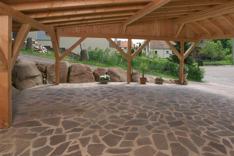 Holzcarport mit Natursteinpflaster und Steingarten