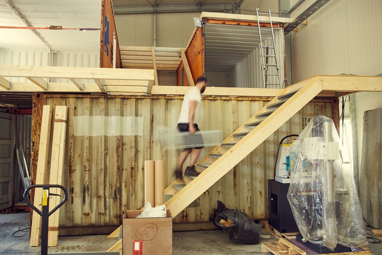 Szene mit einem Mann, der eine Treppe hinaufsteigt, die an einem Container befestigt ist.