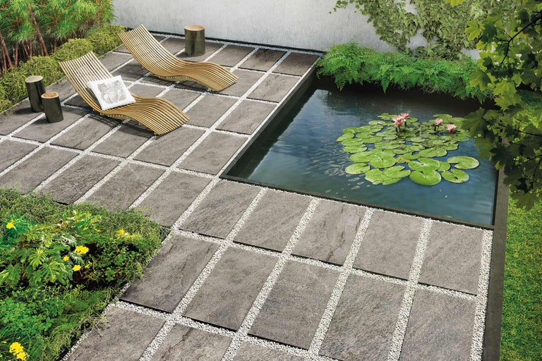 Gartenszene mit Terrassenplatten, Kiesfugen, Teich, Liegestühlen und Bepflanzung