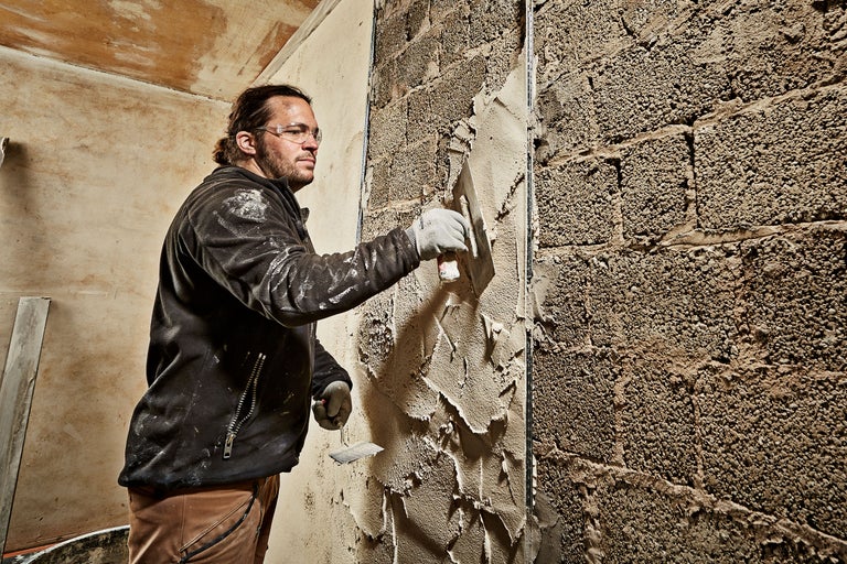Handwerker verputzt eine Ziegelwand mit einer Maurerkelle.