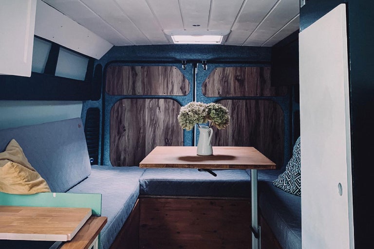 Innenraum eines umgebauten Kastenwagens mit Bett und Tisch