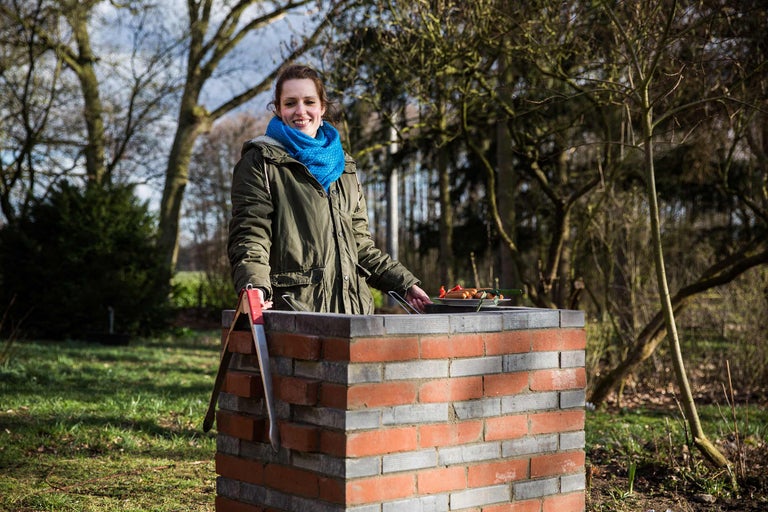 Frau grillt auf einem gemauerten Grill im Garten