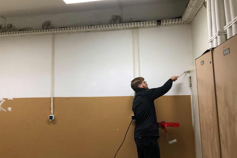 Mann streicht Raum mit Farbroller und Pinsel