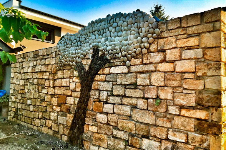 Eine Mauer aus Sandstein mit einem Baumornament aus Kieselsteinen.