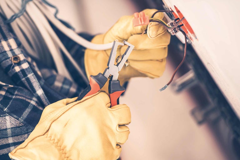 Elektriker mit Abisolierzange bei Elektroinstallation