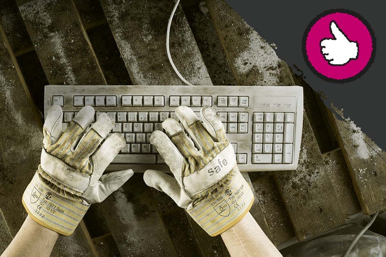Eine schmutzige Computertastatur wird mit Arbeitshandschuhen bedient