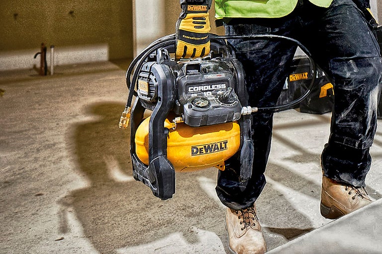 Eine Person trägt einen gelben, kabellosen DeWalt-Kompressor.