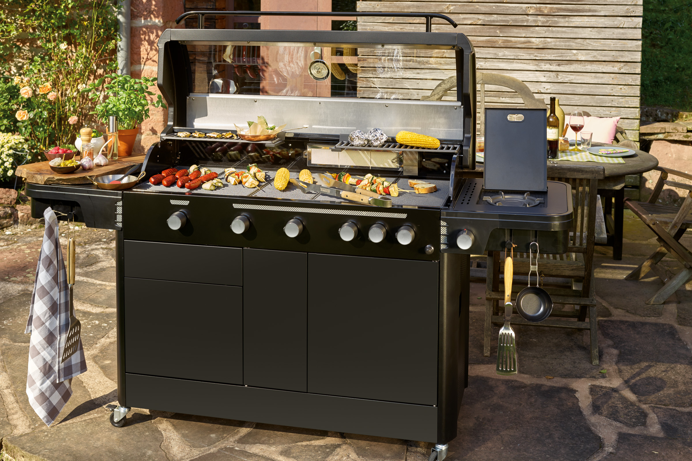 Schwarzer Gasgrill mit Grillgut im Garten.