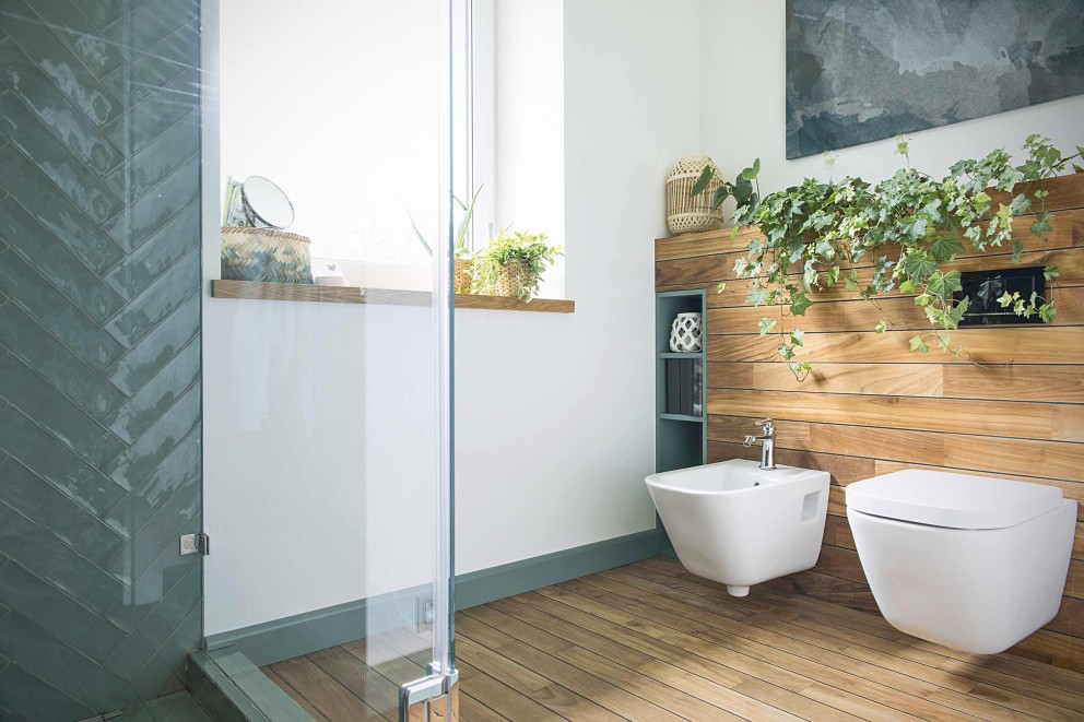 Modernes Badezimmer mit Dusche, Bidet und Toilette an einer Holzwand mit Pflanzen