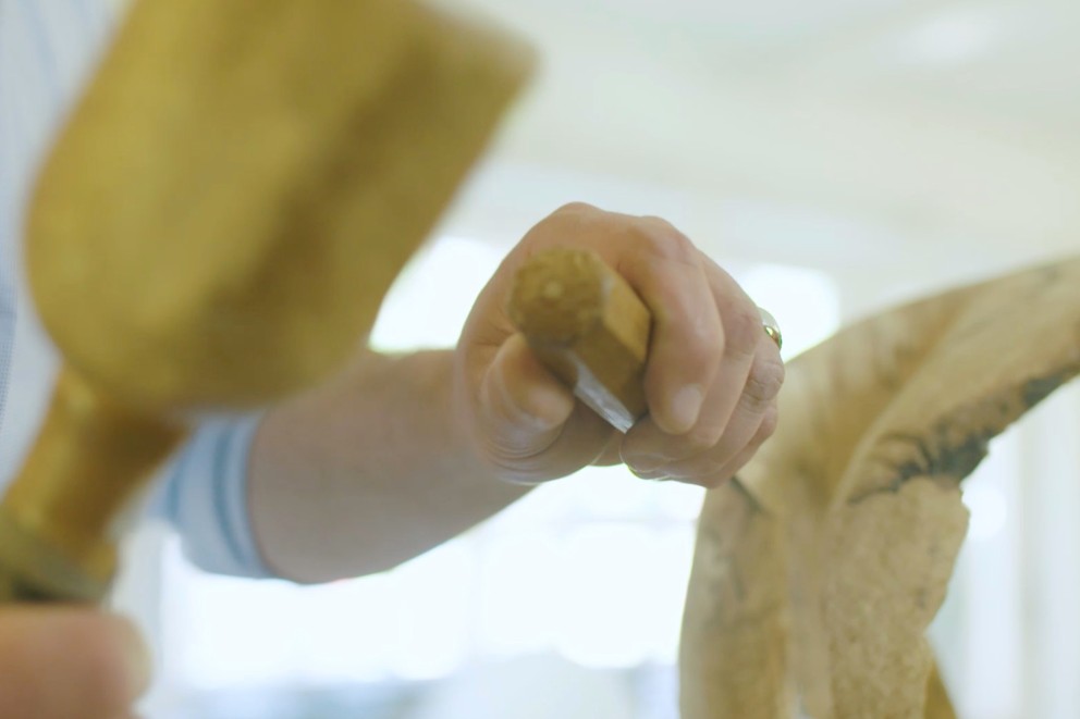 Künstler und Bildhauer Søren Engel bearbeitet eine Holzskulptur mit Hammer und Meißel Künstler und Bildhauer Søren Engel bearbeitet eine Holzskulptur mit Hammer und Meißel