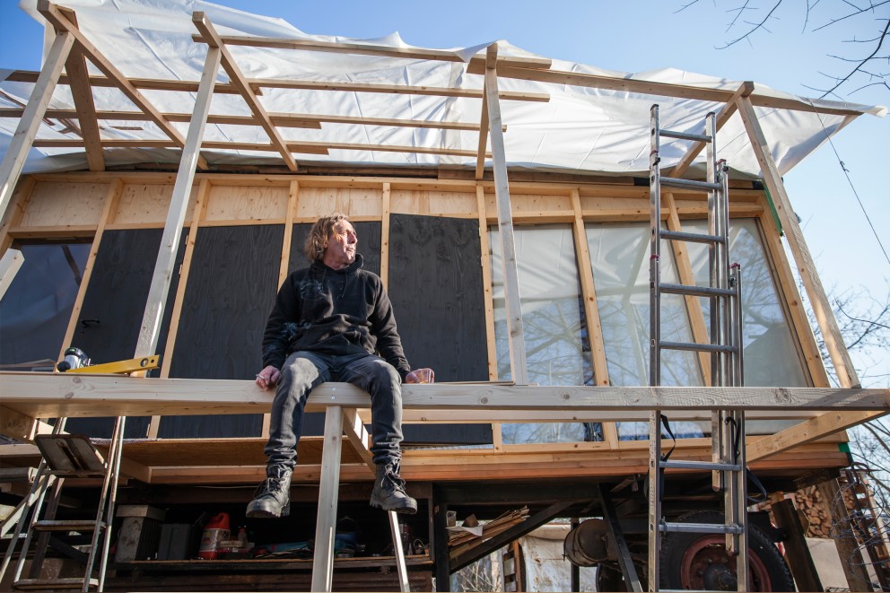 Klaus Madsen sitzt auf dem Gerüst von seinem Tiny House Klaus Madsen sitzt auf dem Gerüst von seinem Tiny House