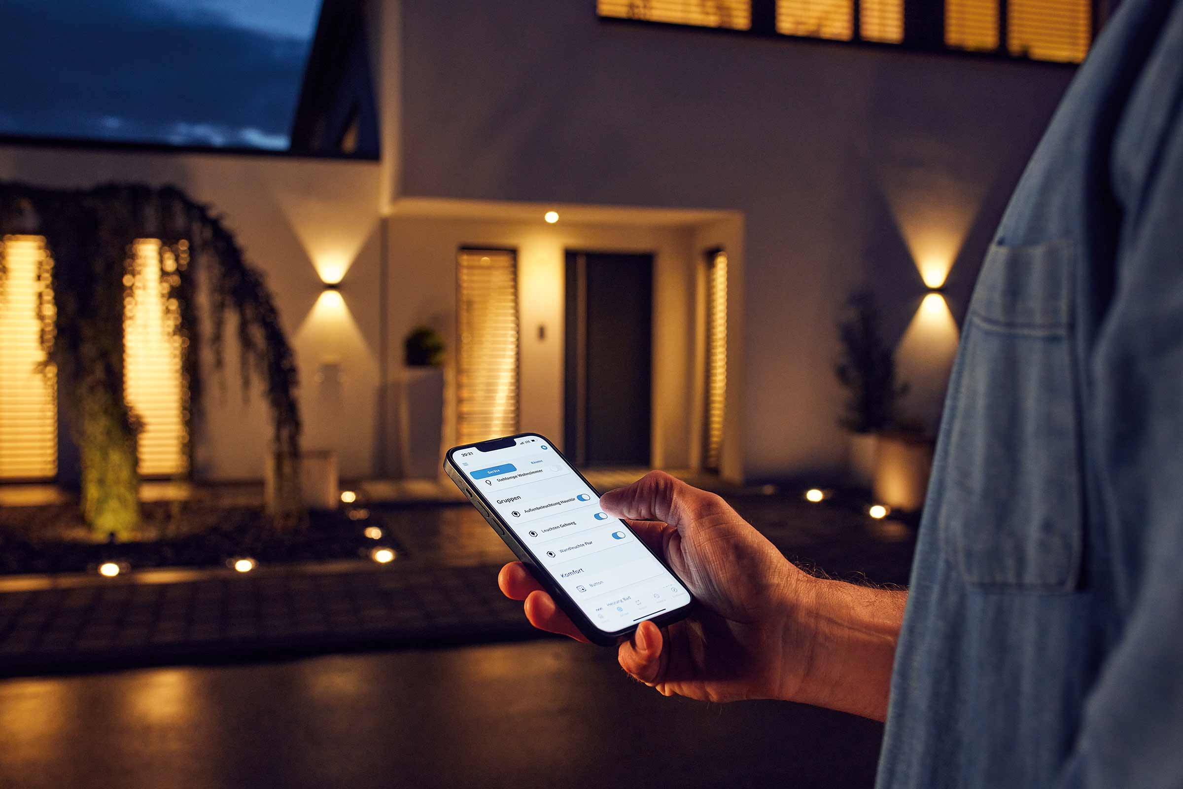 Person steuert Aussenbeleuchtung per Smartphone App am Haus