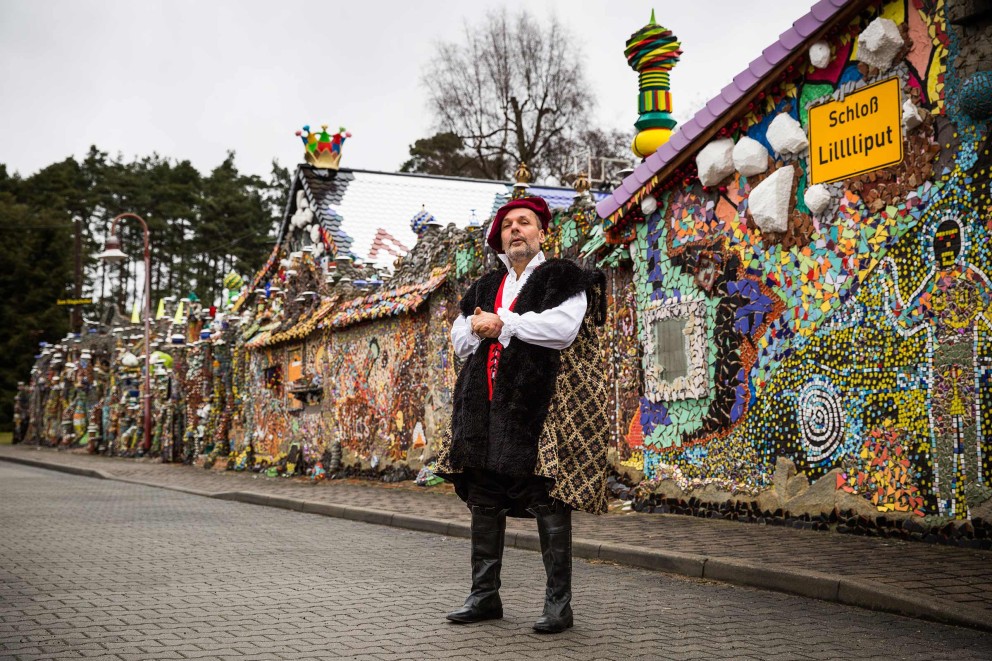 Steffen Modrach steht vor seinem selbstgebauten Hundertwasser Schloss Lilllliput auf der Straße. Steffen Modrach steht vor seinem selbstgebauten Hundertwasser Schloss Lilllliput auf der Straße.