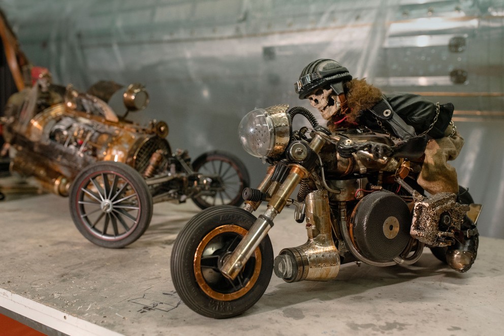„First Ride“, der erste „Speed Devil“, den Steampunk Künstler Georges Ayusawa gebaut hat, ist acht Kilo schwer. Sein Fahrer, „Broken Jaw“, ist eine voll bewegliche Puppe. Auch sie wurde von ihm in akribischer Handarbeit in einer Werkstatt in der schweizerischen Stadt Neuchâtel gefertigt. „First Ride“, der erste „Speed Devil“, den Steampunk Künstler Georges Ayusawa gebaut hat, ist acht Kilo schwer. Sein Fahrer, „Broken Jaw“, ist eine voll bewegliche Puppe. Auch sie wurde von ihm in akribischer Handarbeit in einer Werkstatt in der schweizerischen Stadt Neuchâtel gefertigt.