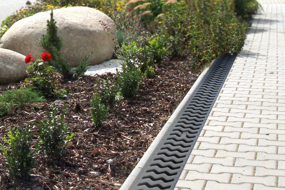 Gartenlandschaft mit Entwässerungsrinne neben Gehwegpflaster