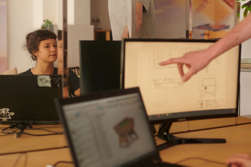 André zeigt Lili am Rechner seinen Tischkicker Bauplan: Die Daten der technischen Zeichnung werden in die CNC Fräse gegeben. André zeigt Lili am Rechner seinen Tischkicker Bauplan: Die Daten der technischen Zeichnung werden in die CNC Fräse gegeben.