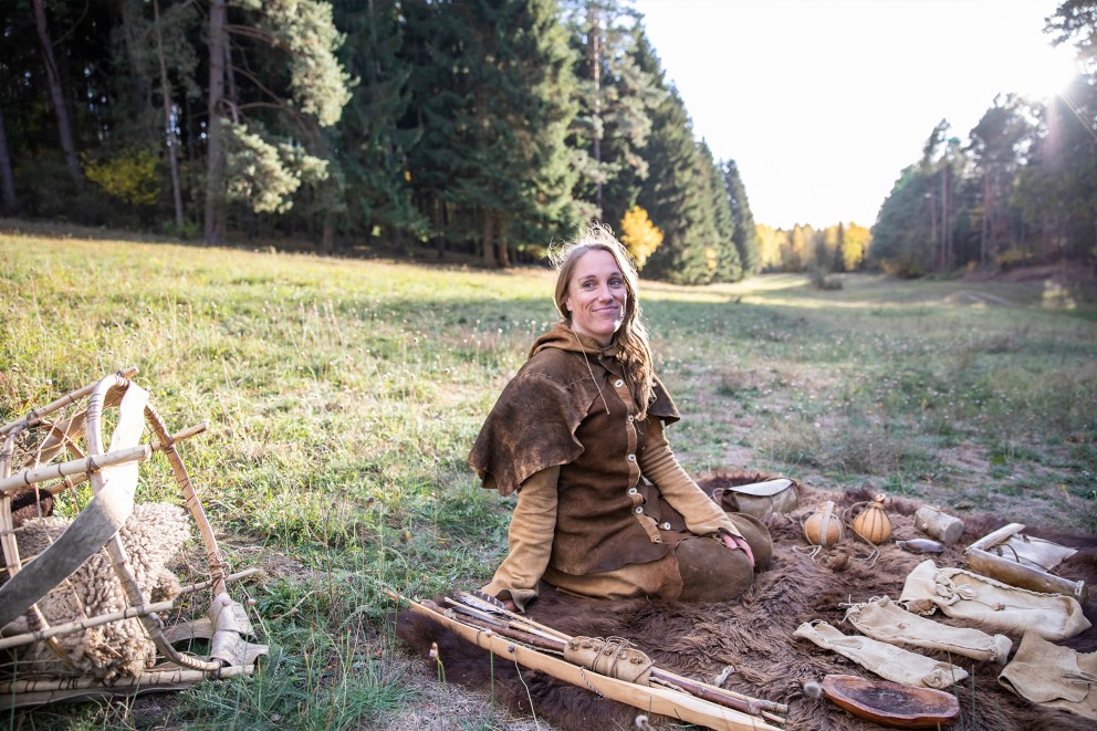 Wildnistrainerin Klara Marie Schulke sitzt auf einer selbst gegerbten Lederdecke, auf der ihre selbst hergestellten Werkzeuge liegen Wildnistrainerin Klara Marie Schulke sitzt auf einer selbst gegerbten Lederdecke, auf der ihre selbst hergestellten Werkzeuge liegen