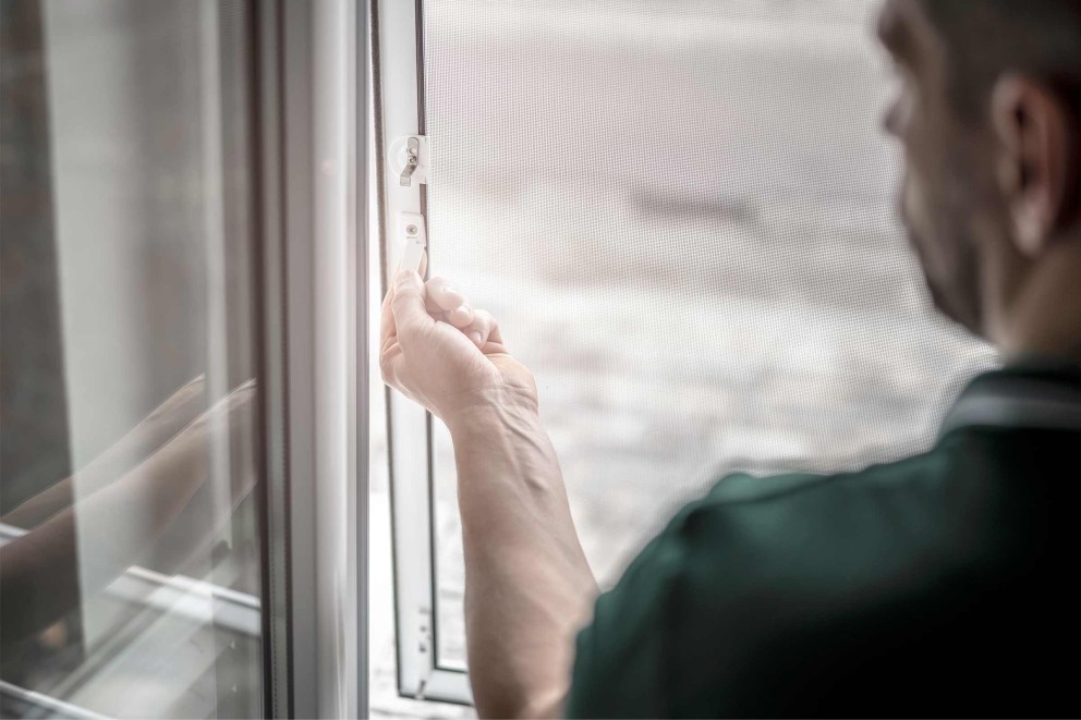Person bedient Insektenschutzgitter am Fenster