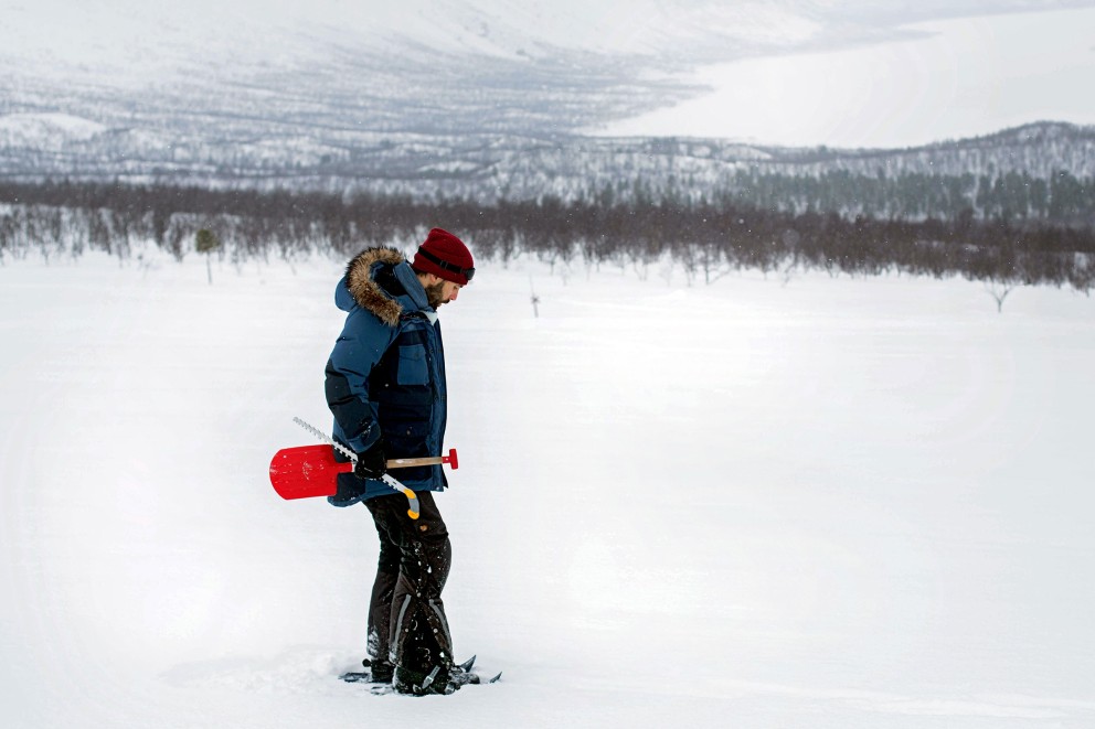 Sascha mit Schaufel und Säge in der Schneelandschaft über dem zugefrorenen Langas See in Schweden. Sascha mit Schaufel und Säge in der Schneelandschaft über dem zugefrorenen Langas See in Schweden.
