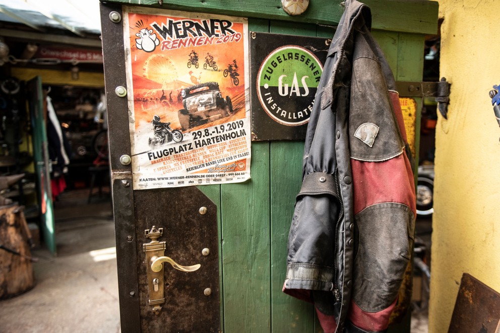 Werkstatt Tür mit Werner Plakat und Arbeitsjacke am Haken. Werkstatt Tür mit Werner Plakat und Arbeitsjacke am Haken.