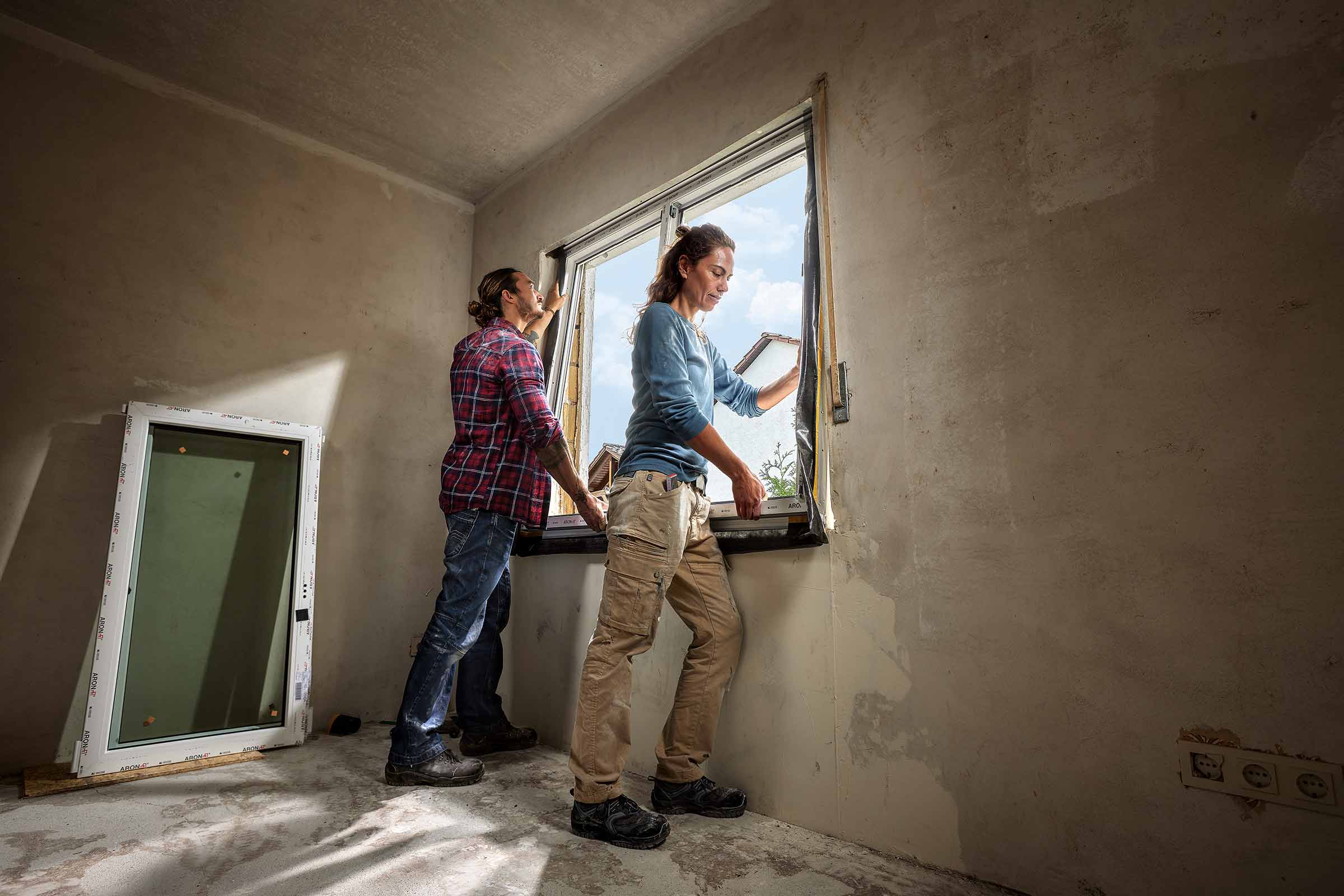 Zwei Personen montieren ein Fenster in einem Raum