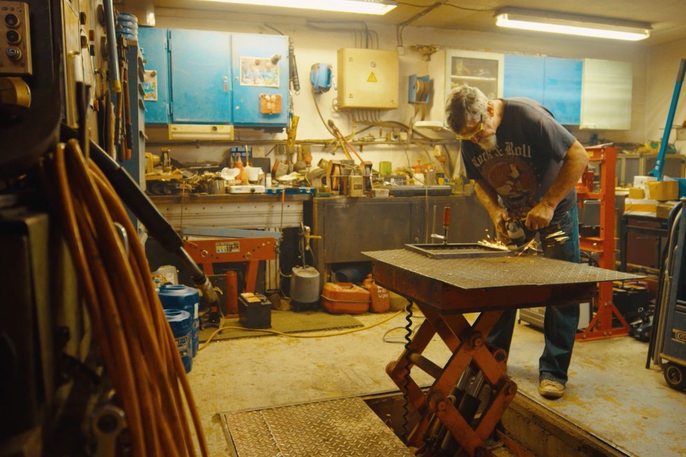 
				Willi flext an einem Stück Metall in seiner Werkstatt

			