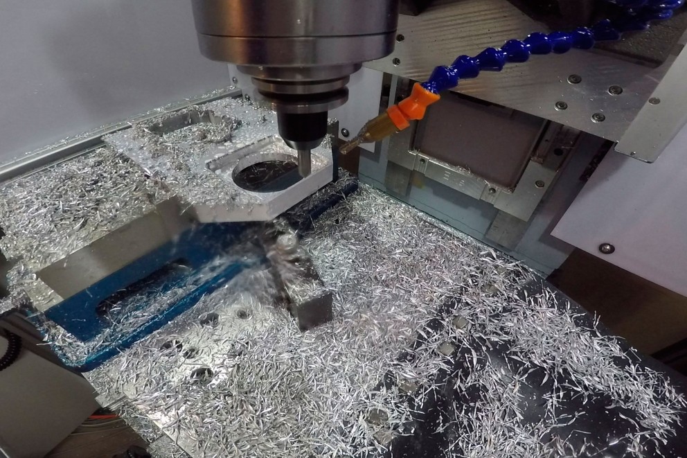 Eine CNC Fräse bearbeitet ein Stahlteil, Späne fliegen umher Eine CNC Fräse bearbeitet ein Stahlteil, Späne fliegen umher