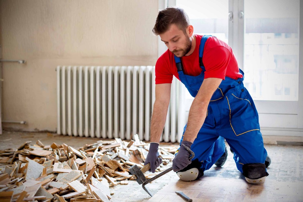 Handwerker entfernt mit einem Hammer und Meißel alte Bodenfliesen