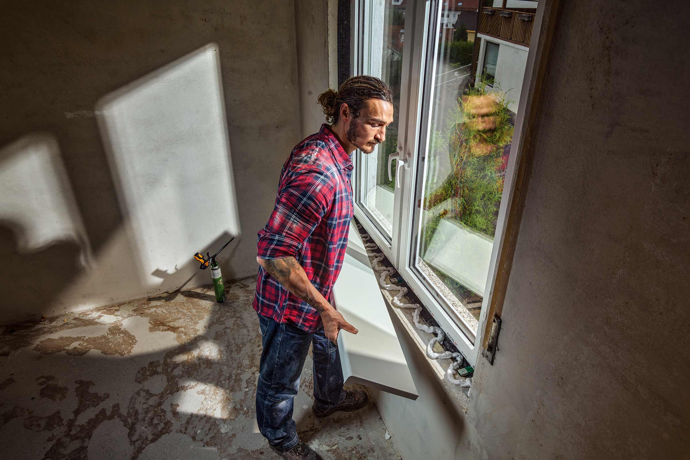 Mann montiert Fensterbrett in einem Rohbau.