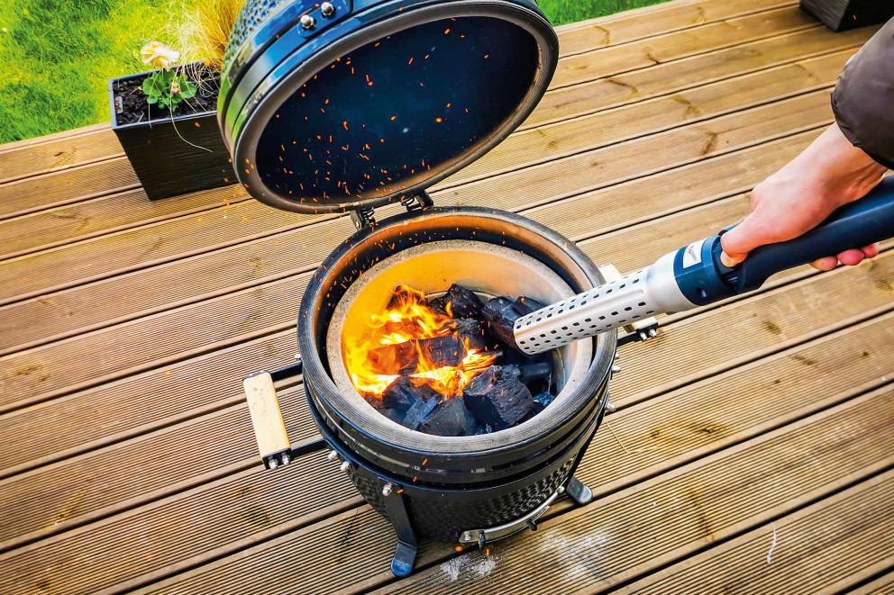 Offener Holzkohlegrill mit Grillanzünder auf einer Holzterrasse