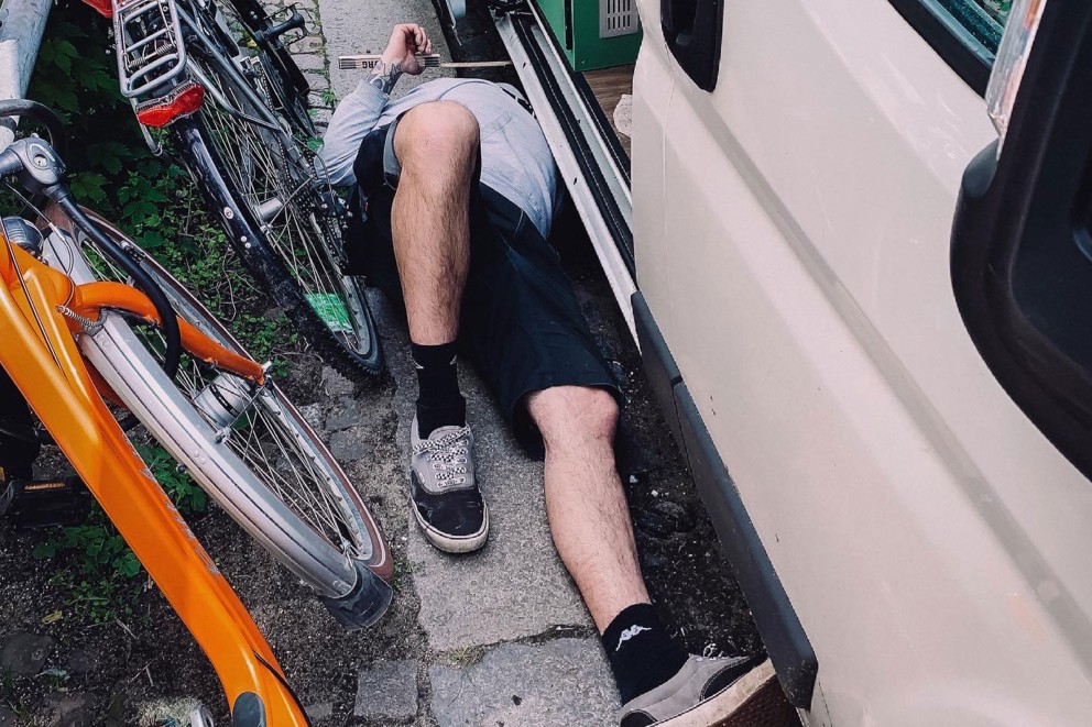 Thomas liegt auf dem Rücken auf dem Bordstein zwischen Fahrrädern und dem Van. Thomas liegt auf dem Rücken auf dem Bordstein zwischen Fahrrädern und dem Van.