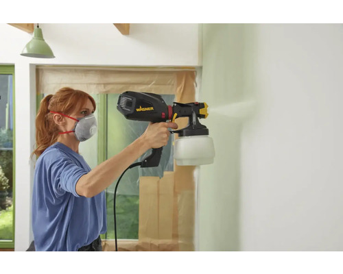 Frau streicht Wand mit Farbsprühsystem von Wagner