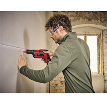 Mann bohrt mit einer Einhell Bohrmaschine ein Loch in eine Wand.