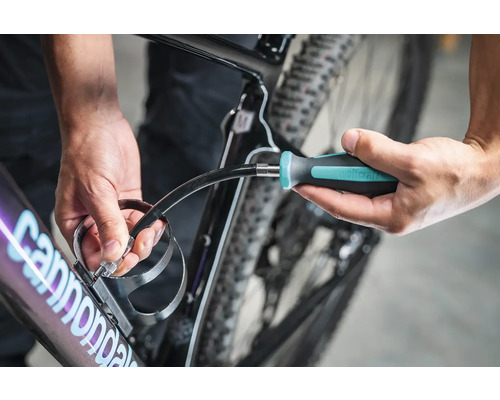 Eine Person befestigt einen Getränkehalter mit einem Schraubendreher an einem Fahrrad.