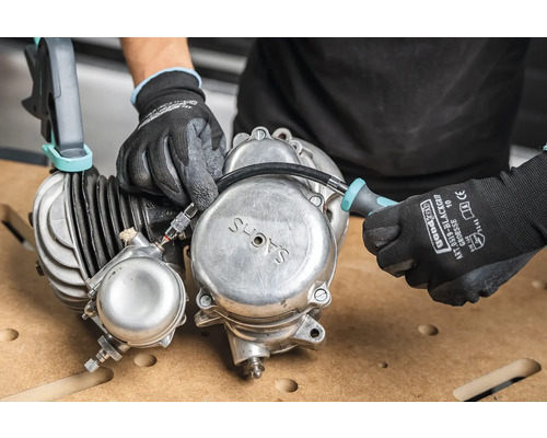 Hände mit Handschuhen arbeiten an einem Sachs Motor mit Schraubenzieher