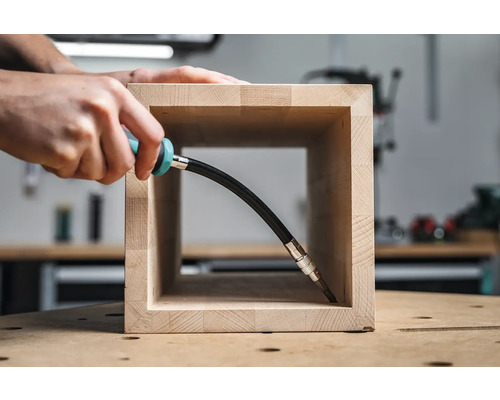 Eine Person arbeitet mit einem flexiblen Schraubendreher an einem Holzwerkstück.