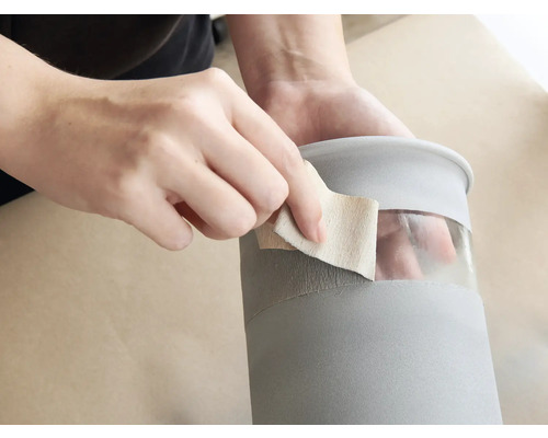 Eine Person schleift einen grauen Behälter mit Schleifpapier.