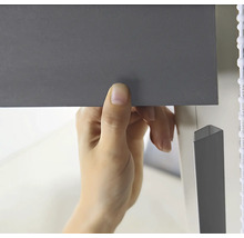 Eine Person befestigt eine Jalousie.