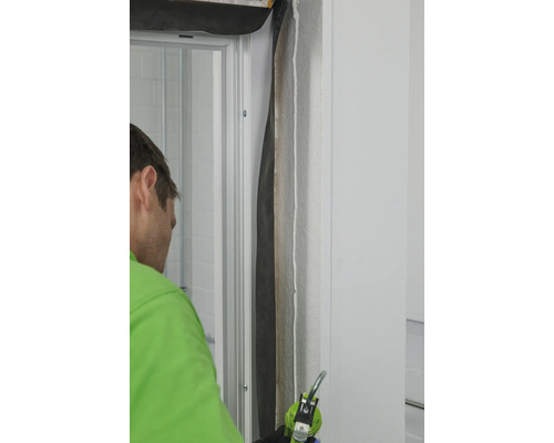 Handwerker dichtet Türrahmen mit Dichtmasse ab