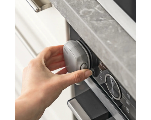 Hand befestigt Kindersicherung am Ofen