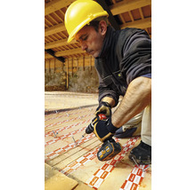 Handwerker mit Schutzhelm und Akkuschrauber bei der Installation von Dämmplatten auf einem Holzboden.