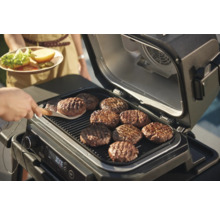 Elektrischer Grill mit mehreren Burger Patties auf dem Rost.