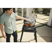 Mann grillt Hähnchen auf einem elektrischen Ninja Grill im Freien.