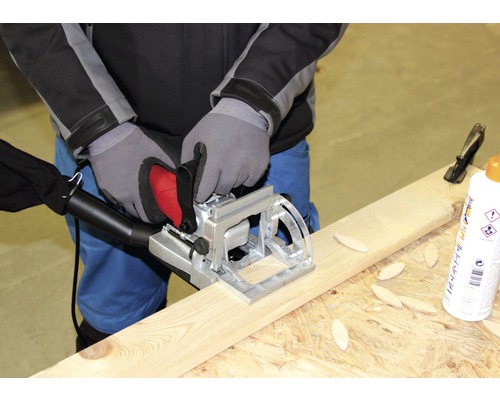 Eine Person benutzt eine Lamellofräse an einem Holzbrett.