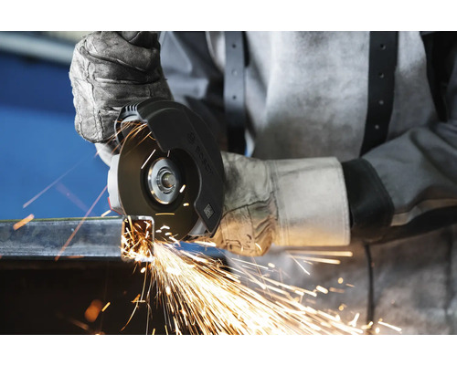 Eine Person trägt Handschuhe und benutzt einen Winkelschleifer zum Schneiden von Metall, wobei Funken entstehen.