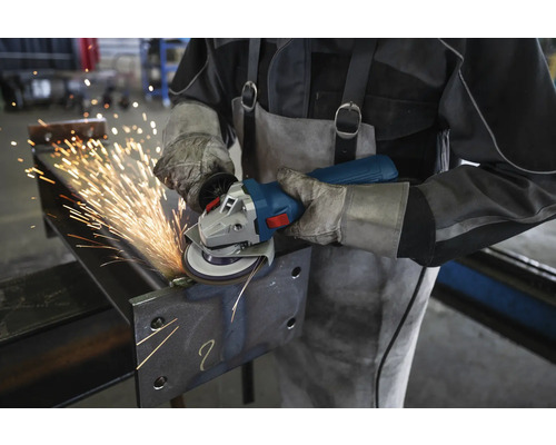 Ein Arbeiter schleift mit einer Flex Metall, wobei Funken sprühen.