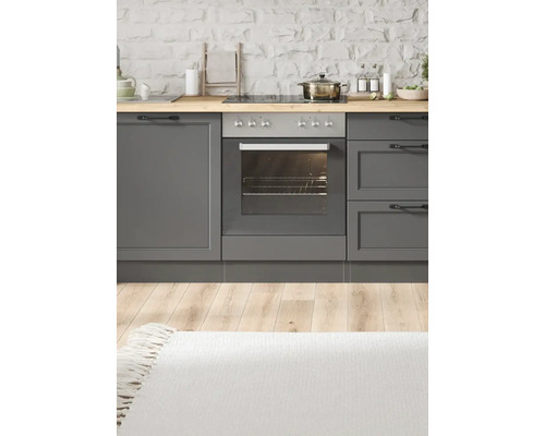 Küchenszene mit grauen Schränken, Herd, Backofen und Holzarbeitsplatte vor einer Steinwand